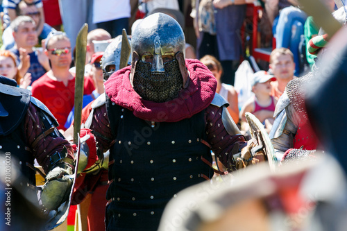 Medieval restorers fight with swords in armor at a knightly tournament