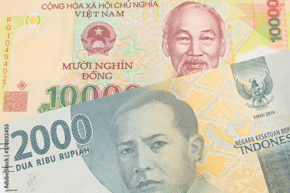 A macro image of a grey two thousand Indonesian rupiah bank note paired up with a yellow one thousand dong bill from Vietnam.  Shot close up in macro.