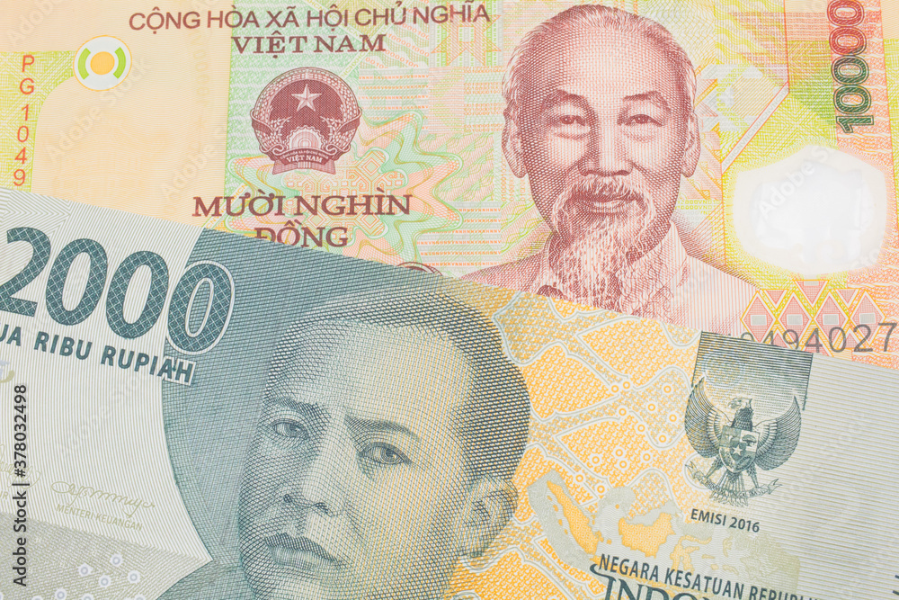A macro image of a grey two thousand Indonesian rupiah bank note paired up with a yellow one thousand dong bill from Vietnam.  Shot close up in macro.