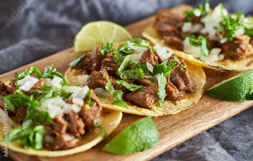 three carne asada mexican street tacos in corn tortilla with lime