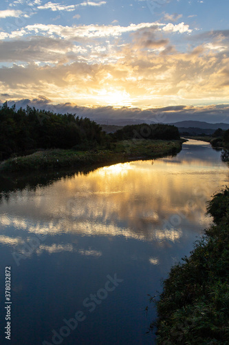 Fototapeta Naklejka Na Ścianę i Meble -  山岳地帯の静かな水面の川に映り込む朝焼け