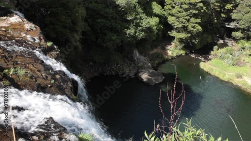 Water Falls over the edge of a tall cliff into the still calm Hatea River below, Whangarei Falls, New Zealand photo