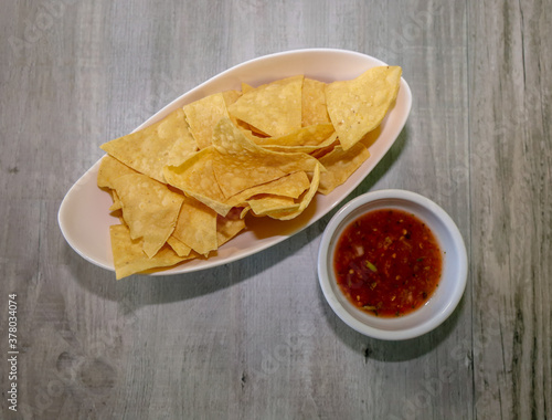 Top view of crispy tortilla chips and red salsa.