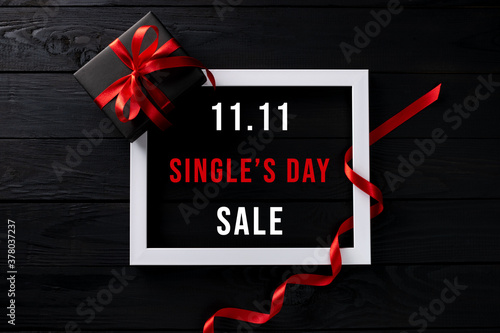 Online shopping of China, 11.11 singles day sale concept. Top view of white picture frame with black gift box on black wooden background with copy space for text 11.11 singles day sale. photo