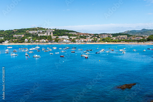 Sant Pol Beach with boats in the sea in a day with some white clouds.