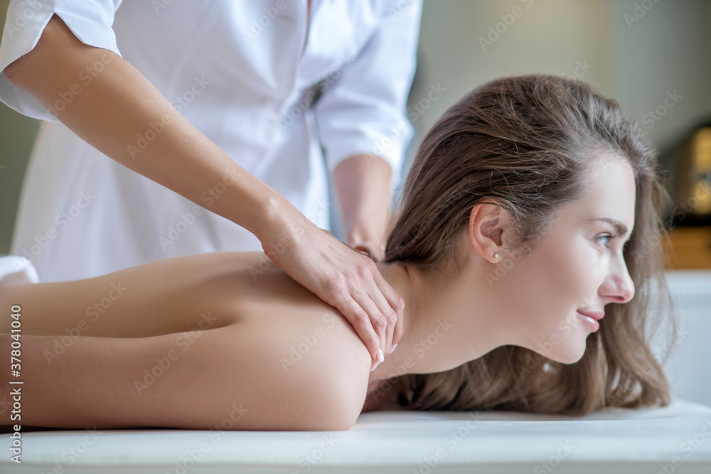 Obraz premium Massage therapist massaging female customers shoulders