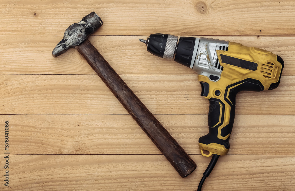 Old drill screwdriver and hammer on a wooden background. Top view