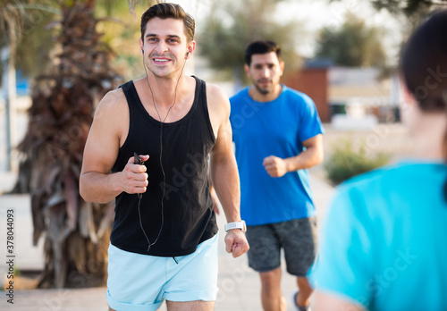 Portrait of adult man who is jogging with friend in the park near ocean.