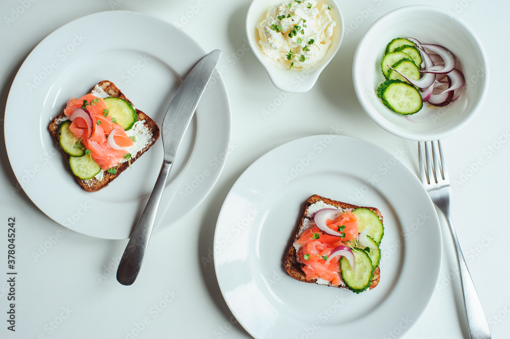 tasty healthy breakfast - salmon and avocado toast with cream cheese, cucumber and red onion on white background tasty healthy breakfast - salmon and avocado toast with cream cheese, cucumber and red onion on white background