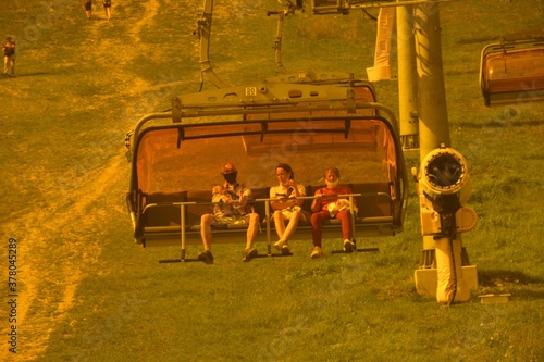 Hikers in protective masks on their faces sit in a cable car to the mountains photo