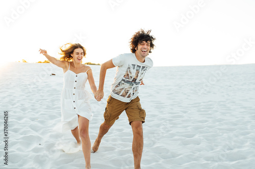 Cheerful couple in love running on the beach and enjoying their vacation