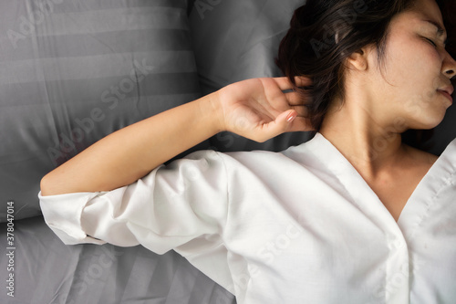 Asian woman suffering from neck pain or a crick in her neck during sleeping in the bed 