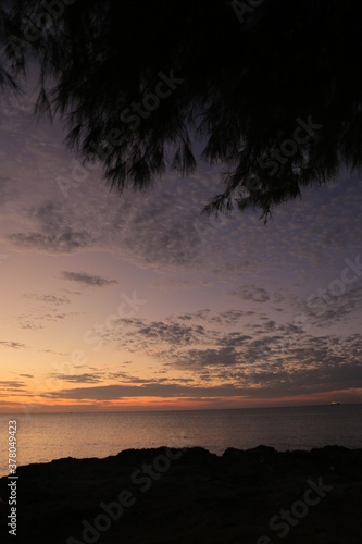 Low orange sunset in dramatic clouds over ocean in Indonesia