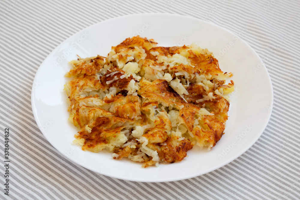 Homemade Fried Hashbrowns on a white plate, side view. Close-up. Homemade Fried Hashbrowns on a white plate, side view. Close-up.