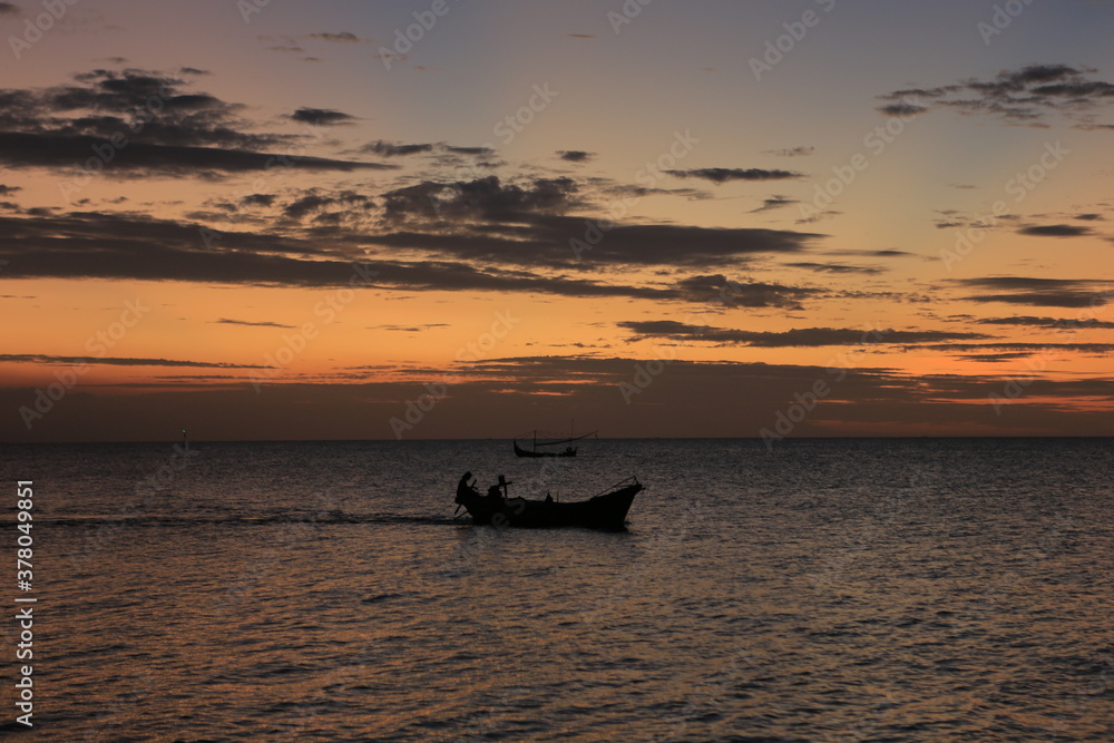 Low orange sunset in dramatic clouds over ocean in Indonesia