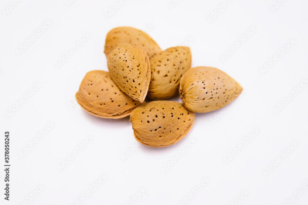 Inshell almonds on a white background. Almonds are arranged in a pile. Inshell almonds on a white background. Almonds are arranged in a pile.