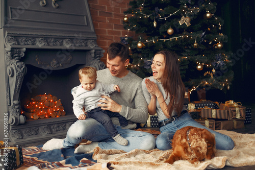 Mother in a gray sweater. Family with christmas gifts. People near fireplace. Family with dog.