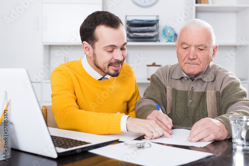 Old man and agent sign lease contract of apartment in agency