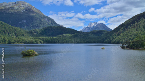 Rock in the clear water of Lake Sylvan, green thick forest and and snowy mountain peak in the background, South Island, New Zealand © Assaf