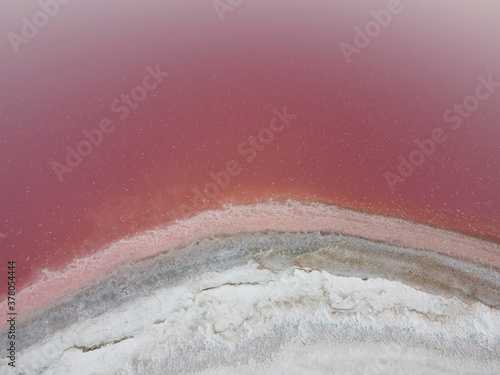 The white shore is covered with salt on a pink lake. Pink Lake has a high content of salt and bacteria that form the pink color of the water.