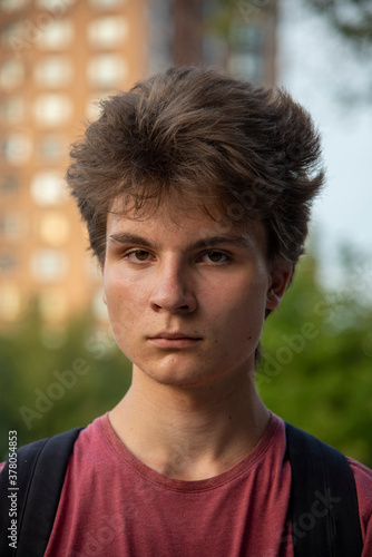 Portrait of a young teenager 17 years old in a red t-shirt with thick hair.
