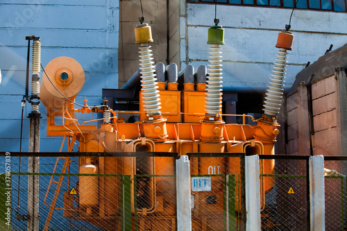 Power generating plant. Orange power transformer on electrical substation. High-voltage equipment