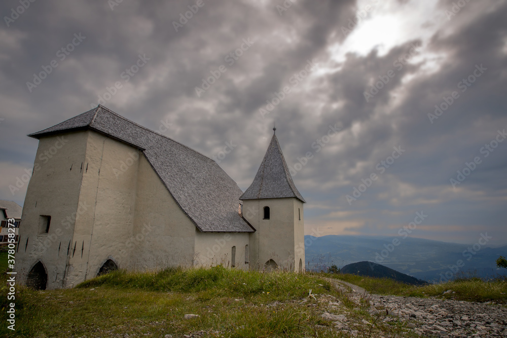 Church of Saint Ursula on the top of Urslja gora, a mountain in the Koroska region of Slovenia on a cloudy day. Thick clouds gathering above the church