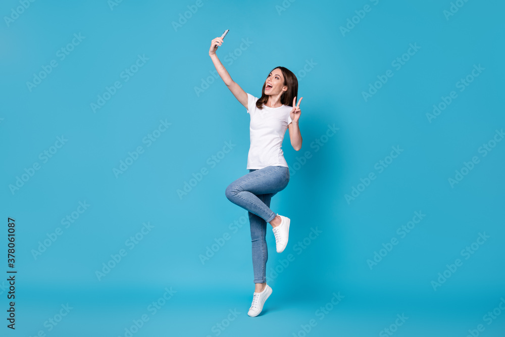 Full length body size view of her she attractive pretty slim fit thin funky cheerful cheery girl blogger jumping taking selfie showing v-sign isolated bright vivid shine vibrant blue color background