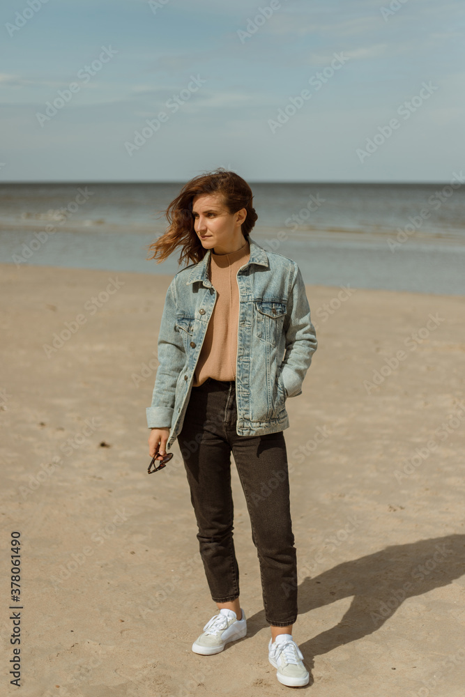 Great pleasure. Charming calm young woman is standing near sea.Attractive woman in jeans with brunette hair.Denim beauty. Great pleasure. Charming calm young woman is standing near sea.Attractive woman in jeans with brunette hair.Denim beauty.