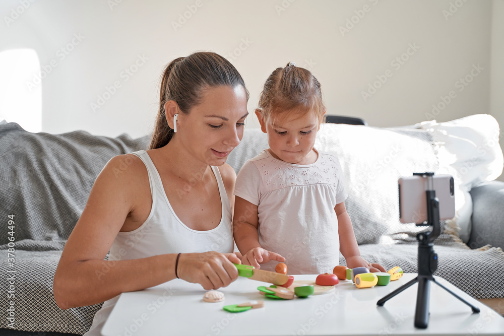 Fototapeta premium Mother with child streaming online video of unboxing wooden toys. Influencer occupation, mommy blog