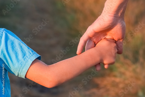 A Hands of a happy child and parent in nature in a park by the road