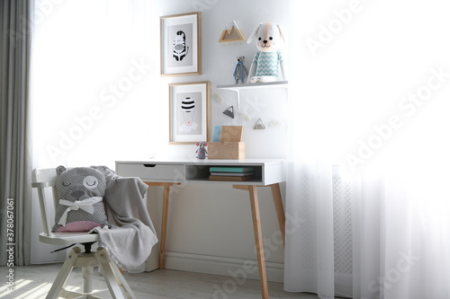 Stylish child's room interior with desk and beautiful pictures