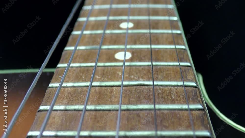 Video of an acoustic guitar neck in perspective. Music and art concept. Black background.