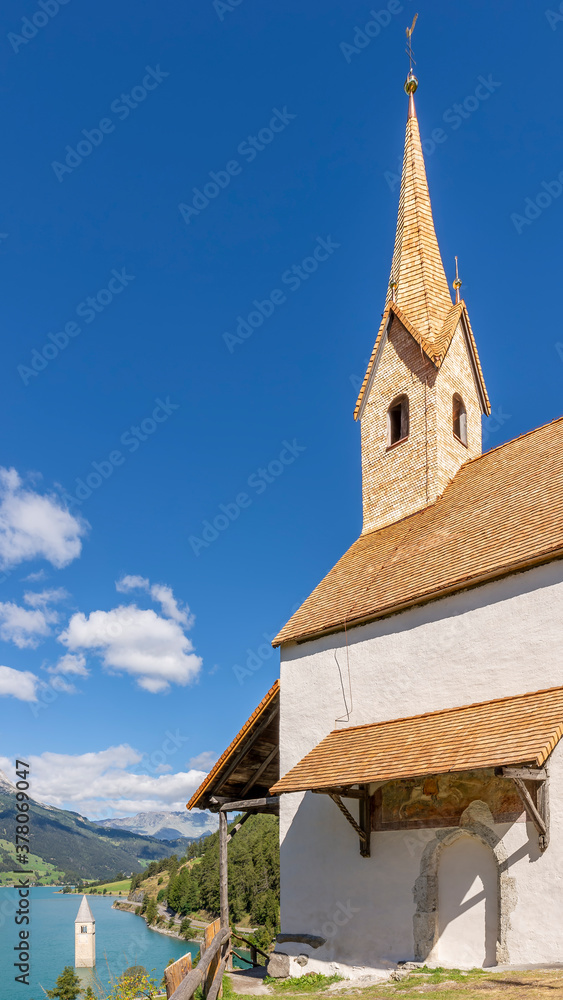 Vertical view of the church of Sant'Anna and Lake Resia, Curon Venosta (Graun), South Tyrol, Italy