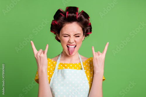 Close-up portrait of her she nice attractive cool naughty glamorous cheerful cheery crazy maid wearing curlers showing double horn symbol grimacing isolated over green color background