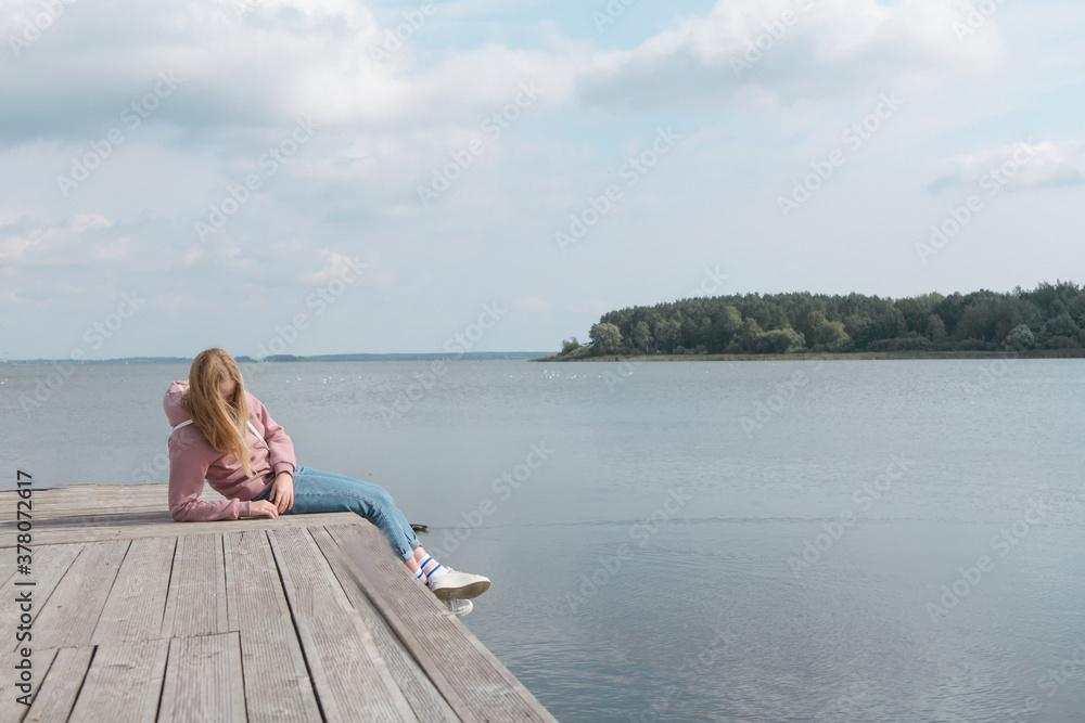  girl  on the pier and looks into the distance. Mental health, sadness, loneliness. Meditation, taking care of herself stayhome, wellness during the lockdown quarantine coronanavirus covid19