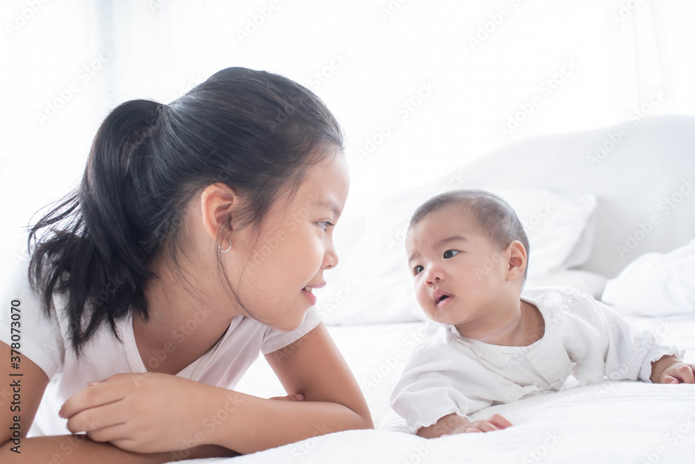 family with children at home. love, trust and tenderness..little sister hugging her newborn brother. toddler kid meeting new sibling. cute girl and new born baby boy relax in a white bedroom. family with children at home. love, trust and tenderness..little sister hugging her newborn brother. toddler kid meeting new sibling. cute girl and new born baby boy relax in a white bedroom.
