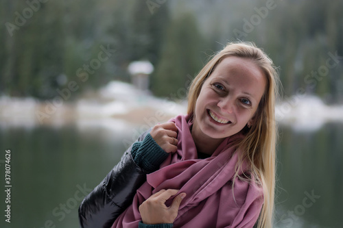 A young woman stands by a winter lake. Girl with long blond hair in winter  © Hanna