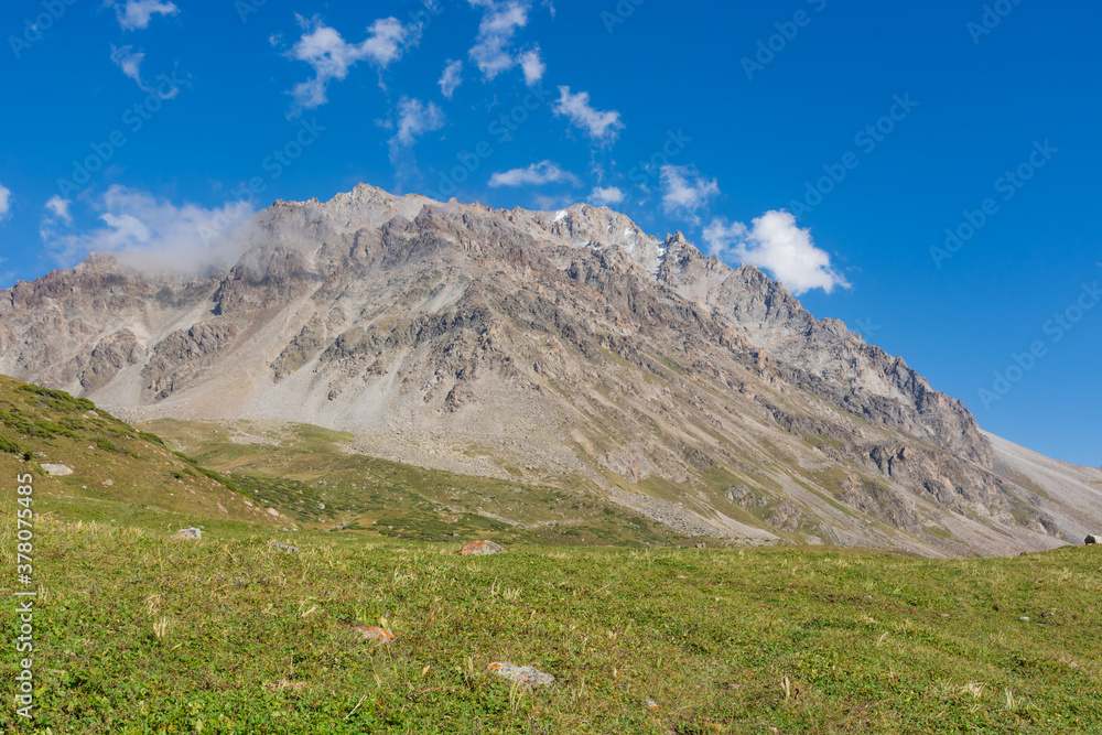 Mountain landscape view in Kyrgyzstan. Green grass in mountain valley view. Mountain panorama.