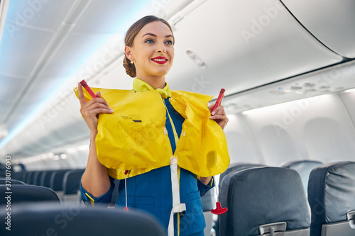 Flight attendant on board an airplane holding life jacket before flight procedure photo