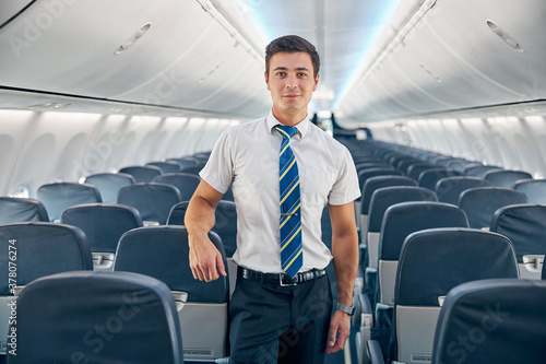 Young man standing in the empty board of commercial airplane