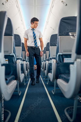 Man in white shirt and dark pants looking to the cozy passenger chairs