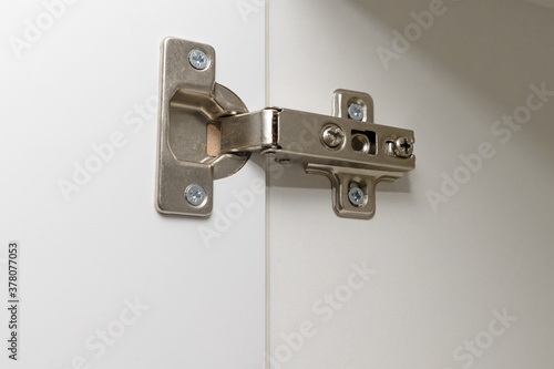 metal furniture hinge mounted on the door of a white cabinet