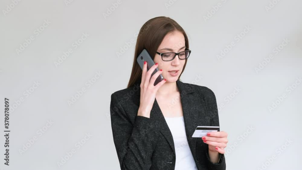 Bank call. Data verification. Confident business woman in glasses black blazer using mobile phone credit card isolated on gray copy space background. Customer support. Cashless payment. Bank call. Data verification. Confident business woman in glasses black blazer using mobile phone credit card isolated on gray copy space background. Customer support. Cashless payment.