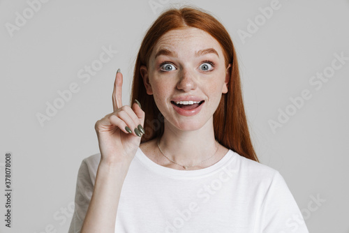 Image of surprised ginger beautiful girl pointing finger upward