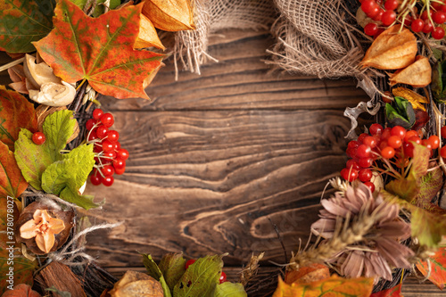 wreath of autumn leaves and natural materials on rustic wooden boards. Top view