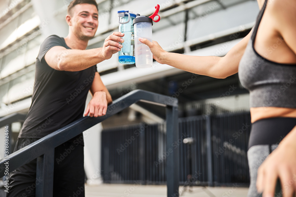Cheerful couple drinking water after training together Cheerful couple drinking water after training together