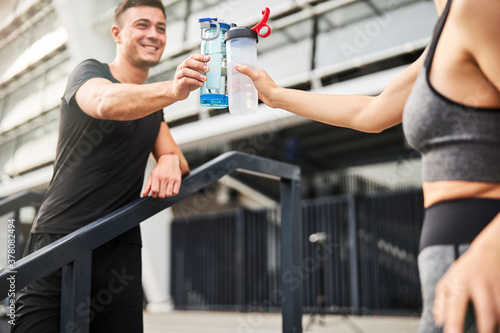 Cheerful couple drinking water after training together