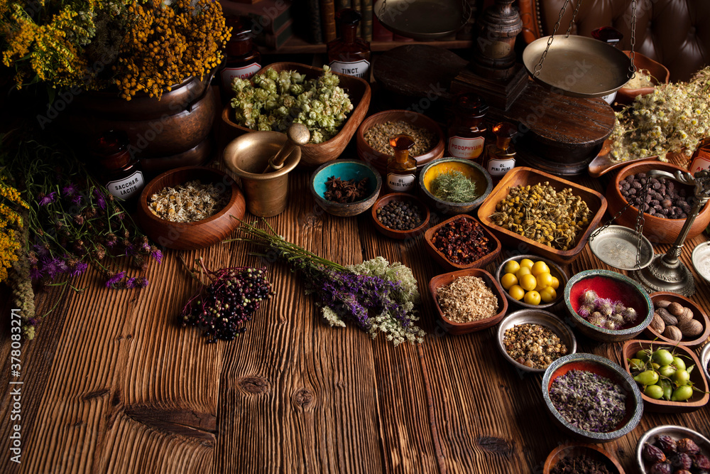 Natural medicine background. Assorted dry herbs in bowls and brass mortar on rustic wooden table. Natural medicine background. Assorted dry herbs in bowls and brass mortar on rustic wooden table.