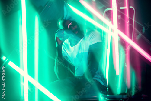 Geometric lines. Cinematic portrait of stylish young man in neon lighted room. Bright neoned colors. African-american model  musician indoors. Youth culture in party  festival style and music concept.